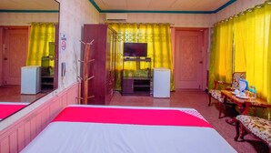 A hotel room with a bed, a desk with a chair, a TV, and a wardrobe. - OYO 1140 Maganda Hotel (Tagaytay)