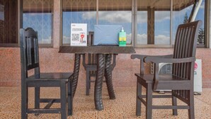A covered outdoor seating area with a table and two chairs, a laptop, and a bottle of hand sanitizer. - OYO 1140 Maganda Hotel (Tagaytay)