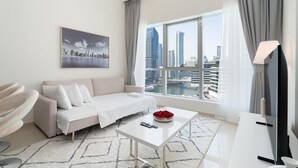 Een moderne woonkamer met een witte bank, een salontafel en uitzicht op een stadsgezicht door grote ramen.