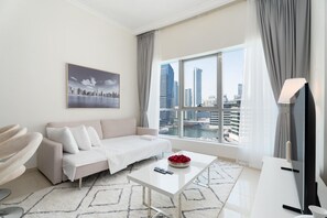 Un salon moderne avec un canapé blanc, une table basse et une vue sur la ville à travers de grandes fenêtres.