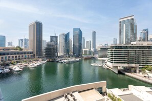 Un port de plaisance où sont amarrés des bateaux, entouré d’immeubles modernes de grande hauteur.