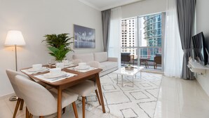 Ein modernes Wohnzimmer mit Essbereich, einer Couch, einem Couchtisch und einem großen Fenster mit Blick auf die Stadt.