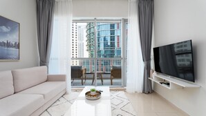 Ein modernes Wohnzimmer mit einer Couch, einem Couchtisch, einem Flachbildfernseher und einem Balkon mit Blick auf die Stadt.
