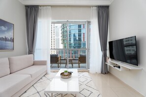 A modern living room with a sofa, a coffee table, a flat-screen TV, and a balcony with city views. - Fabulous 1 BR at Dubai Marina (Dubai)