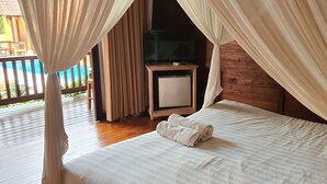 A bedroom with a bed, a TV, and curtains. - Buah Nagasari Ubud Villa (Ubud)
