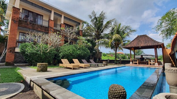 A swimming pool with lounge chairs, a gazebo, and a building with balconies. - Buah Nagasari Ubud Villa (Ubud)