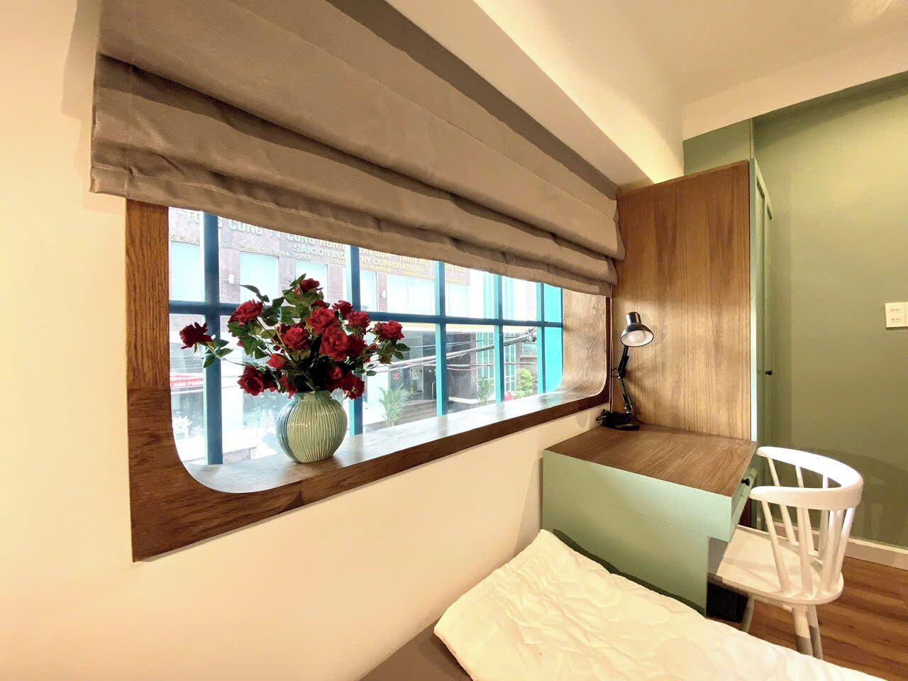 A small room with a window, a desk, a chair, and a lamp.