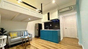 Un espacio habitable compacto con kitchenette, un sofá, una mesa de comedor y una puerta blanca.