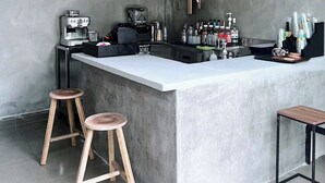 Una cocina moderna con una isla central, taburetes de bar, lámparas colgantes y una cafetera.