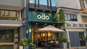 Un edificio moderno con un restaurante llamado 'odo' en la planta baja, que cuenta con terraza y una entrada visible.