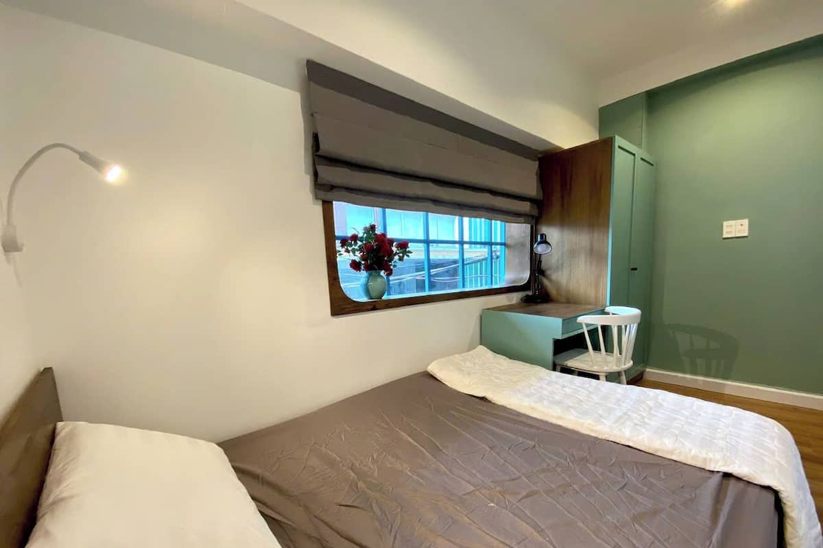 A bedroom with a bed, a window with a view, a bedside table, and a chair.