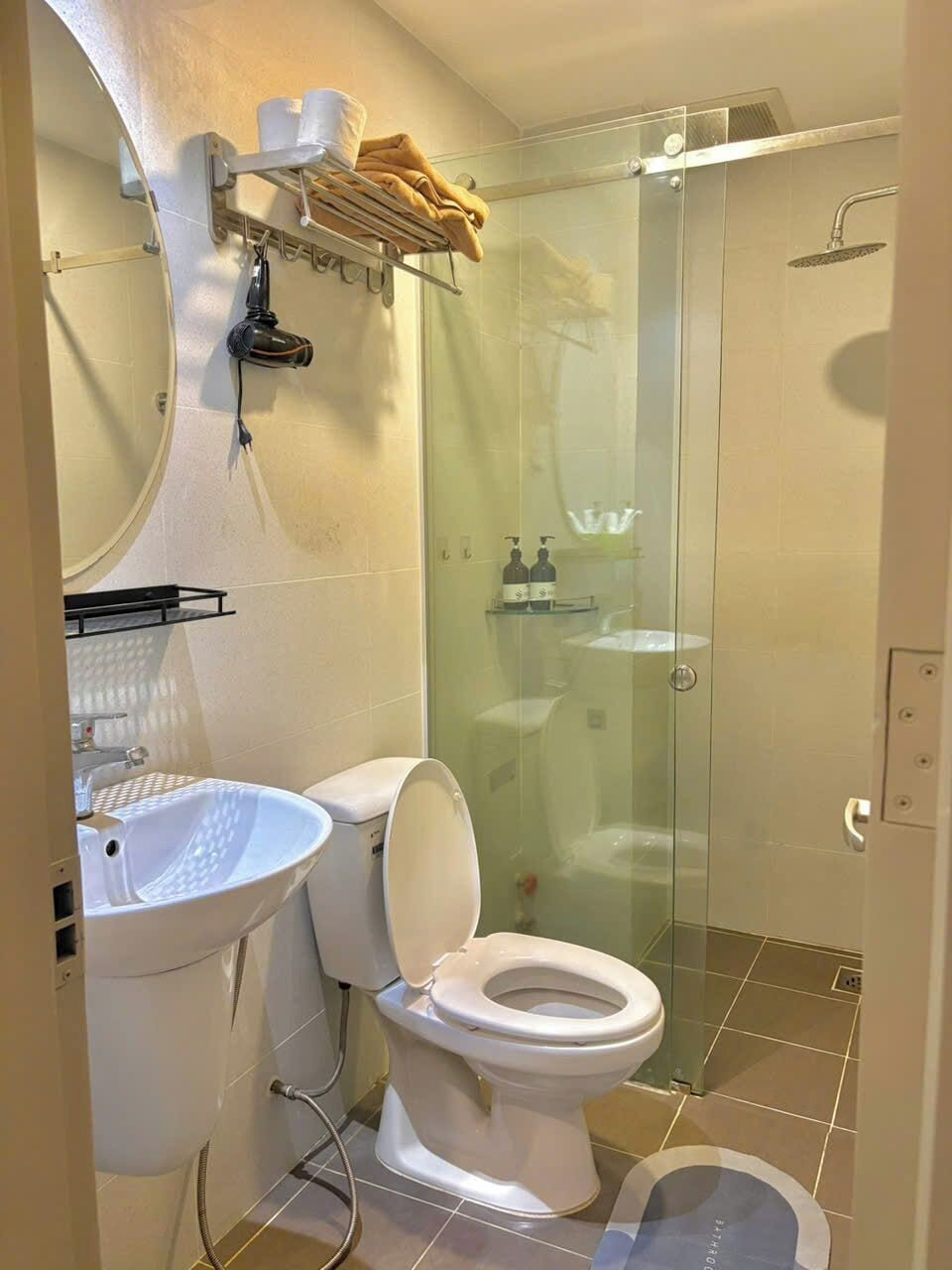 Une salle de bain équipée de toilettes, d’un lavabo et d’une douche à parois en verre.