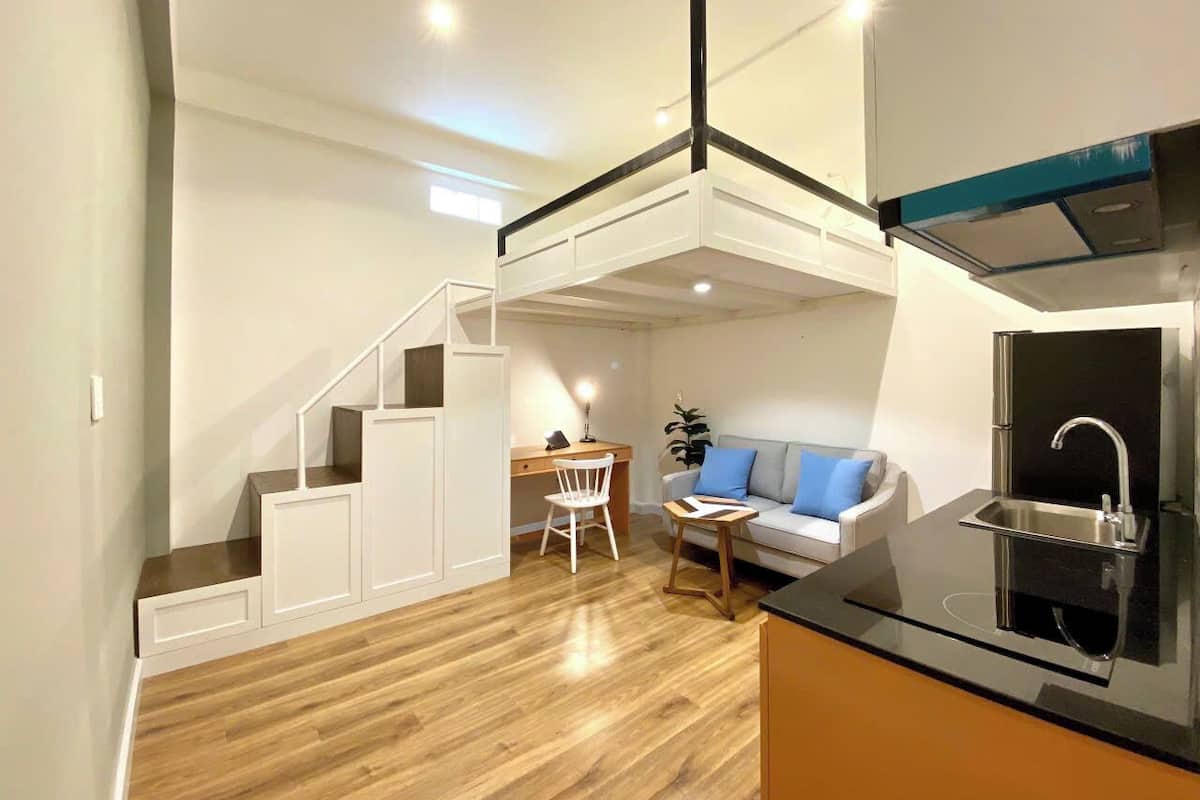 A compact living space with a kitchenette, a dining area, and a seating area with a sofa and a chair.