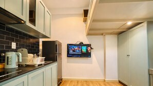 Una cocina con televisión integrada, hervidor de agua y cafetera.