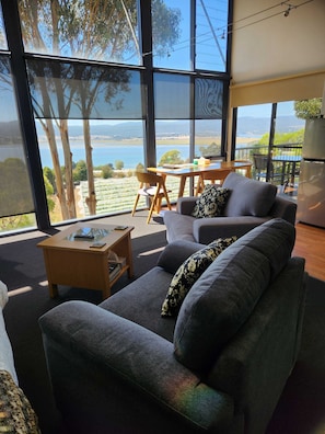 A modern living room with a large window, a sofa, a coffee table, and a dining area.