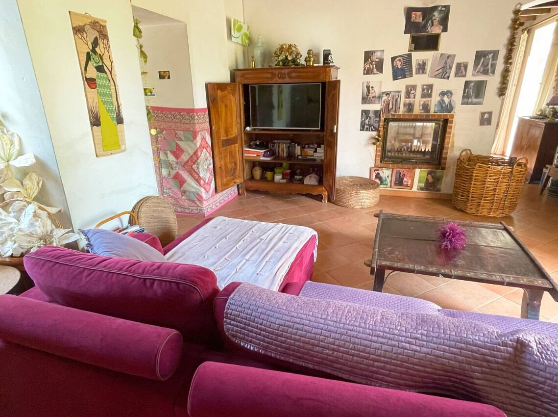 Una sala de estar con sofá, televisor, estantería y chimenea.