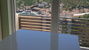 Un balcone con vista su una cittadina costiera e delle colline.