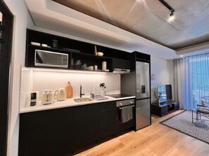 Une cuisine moderne avec des meubles noirs, un plan de travail blanc et un four à micro-ondes encastré.