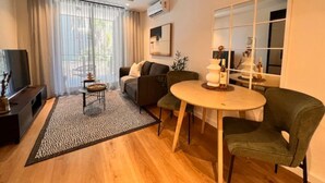 A modern living room with a sofa, a coffee table, and a dining table. - Lifestyle Apartment at Stationhouse (Cape Town)