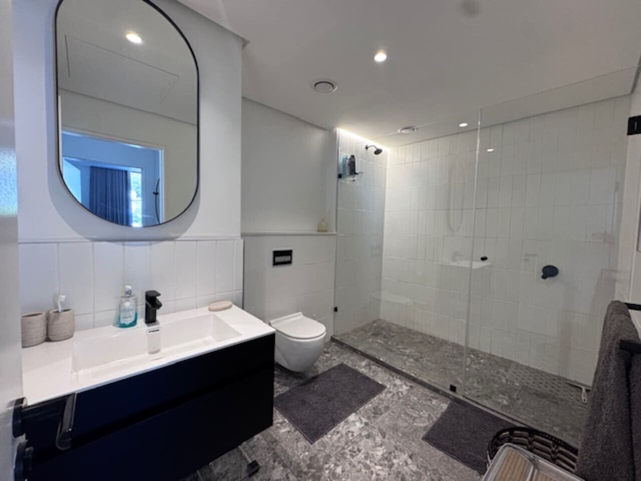 Ein modernes Badezimmer mit einem weißen Waschbecken, einer Toilette und einer Duschkabine.