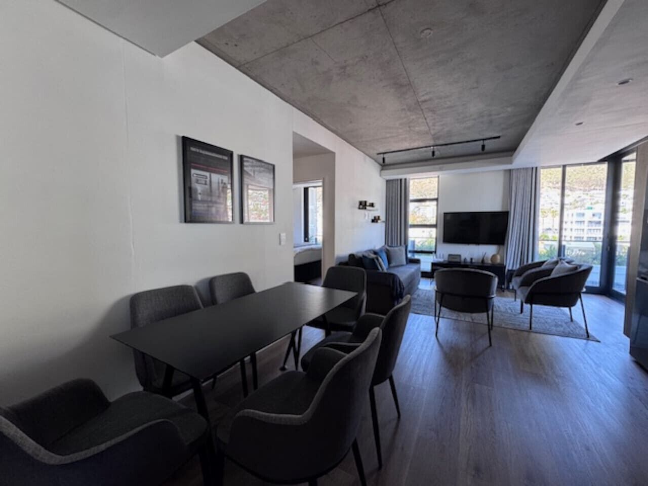 A modern conference room with a long table and chairs, a sofa, and a TV.