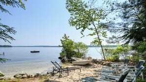 Une plage au bord du lac, avec des chaises longues, un petit bateau et un quai.