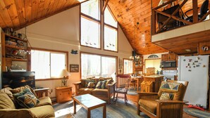 Un intérieur de chalet chaleureux comprenant un salon, un coin repas et une cuisine.