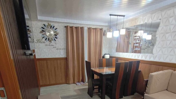 Un comedor con una mesa y sillas de madera, un sofá y un reloj de pared decorativo.