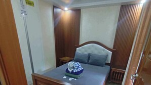 Un dormitorio con una cama de madera, una mesita de noche pequeña y una mesita auxiliar.