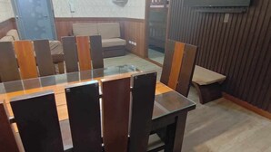 Un comedor con una mesa de vidrio y sillas de madera, un sofá y un televisor montado en la pared.
