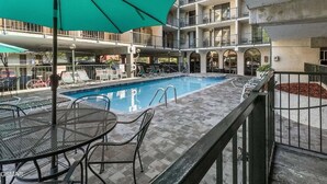 A rooftop pool area with a swimming pool, lounge chairs, and a table with an umbrella.