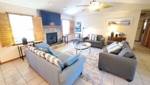 A living room with a fireplace, sofas, a coffee table, and a ceiling fan.