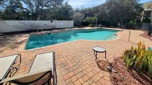 A rectangular swimming pool with a brick patio, lounge chairs, and a small table. - Ocean Reef 306 3 Bedroom Condo (St. Augustine)
