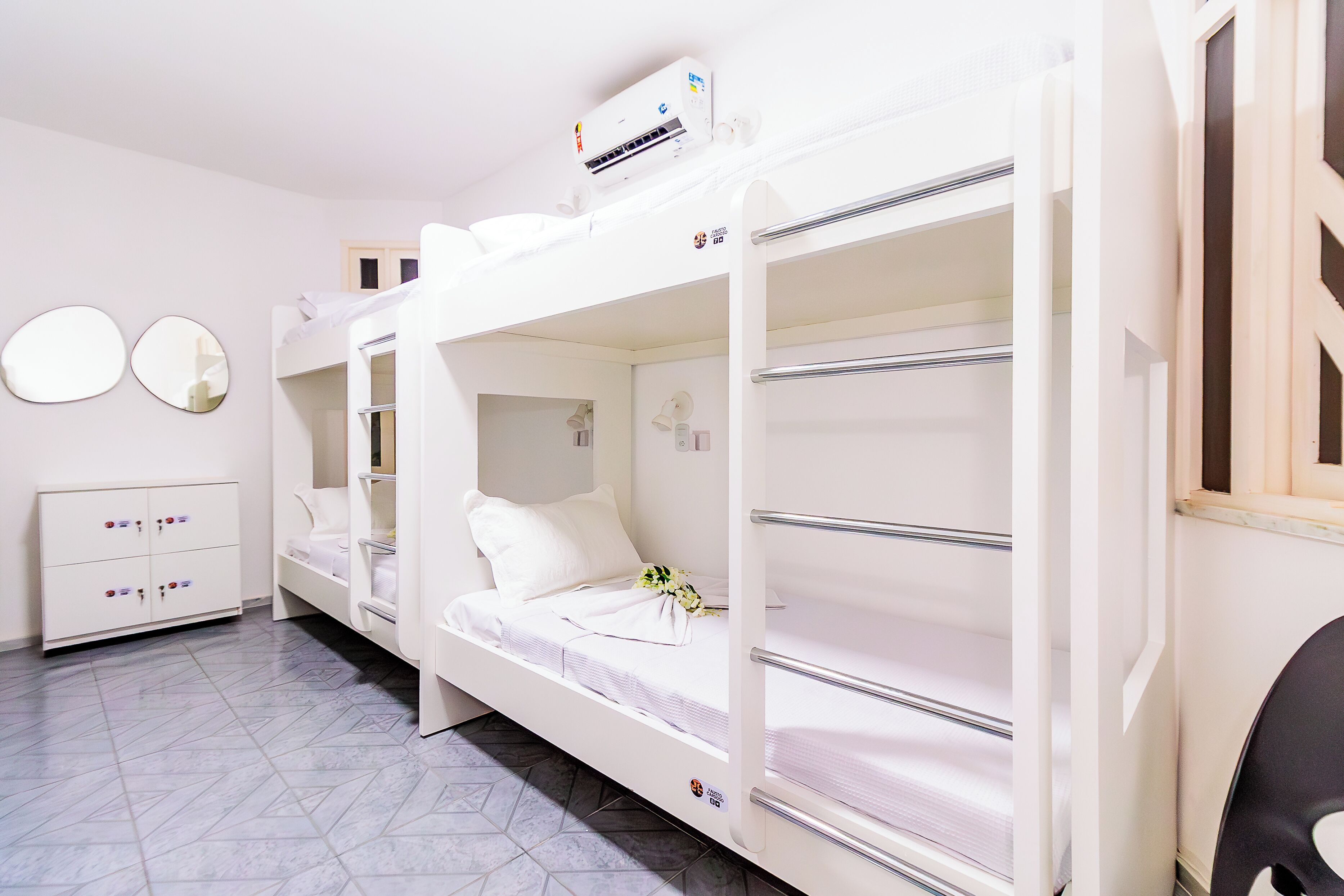 A bunk bed room with a white dresser, a mirror, and a wall-mounted air conditioner.