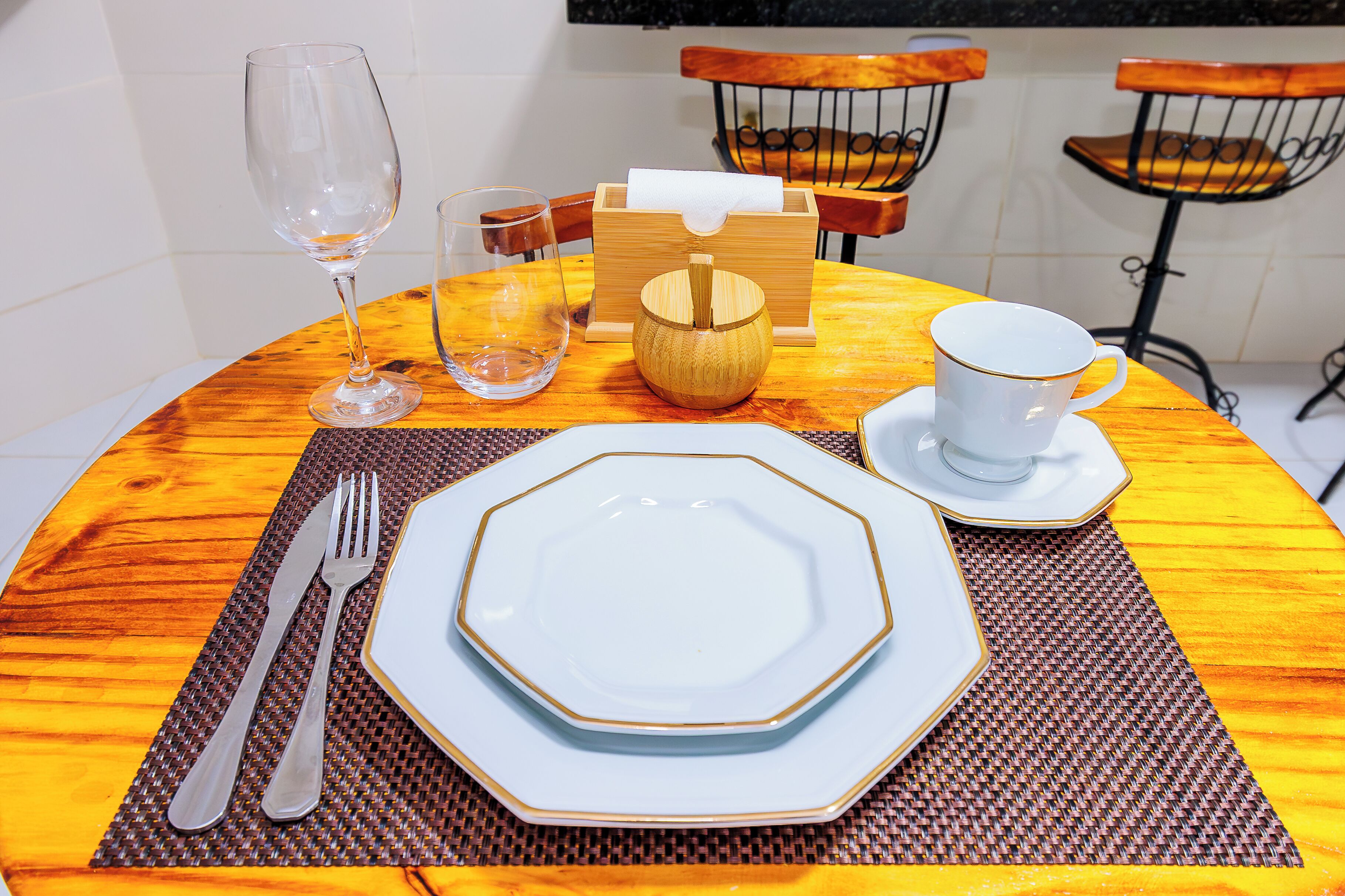 Una mesa redonda de comedor con un plato blanco, una taza, un vaso y un portalápices.