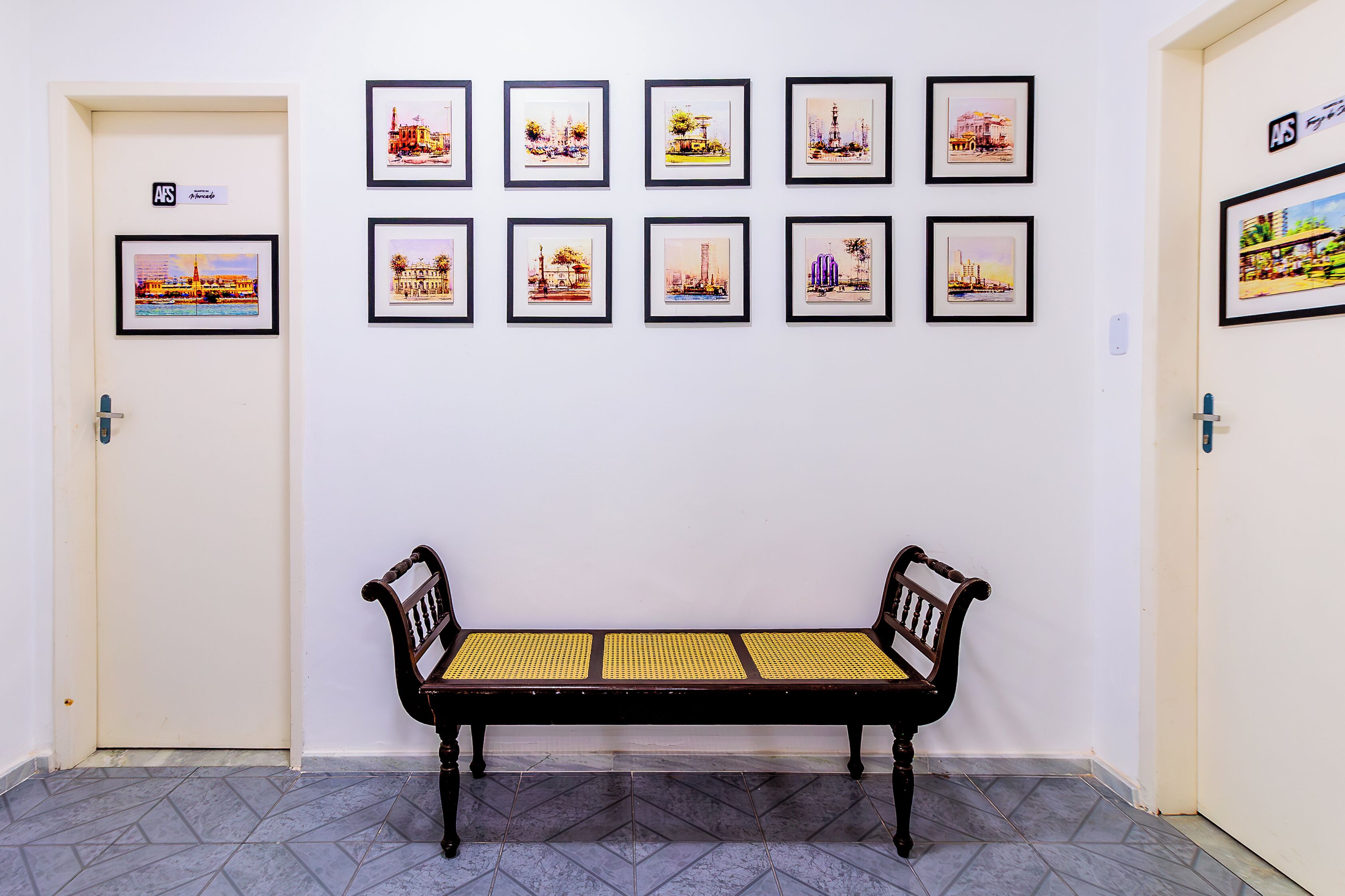 A hallway with a bench and framed pictures on the wall.