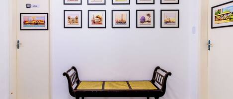 A hallway with a bench and framed pictures on the wall.