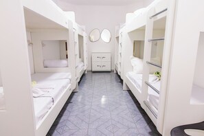 Una camera d'albergo con letti a castello, una cassettiera e uno specchio appeso al muro.