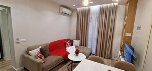 A modern living room with a sofa, a small round table, and a flat-screen TV. - Arkle Apartment 1 (Tirana)