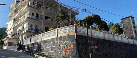 A multi-story building with balconies, a stone wall with the name "Villa 88," and a sign for "Local Food Taste."