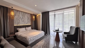 Una habitación de hotel moderna con una cama grande, un área de descanso con mesa y un televisor.