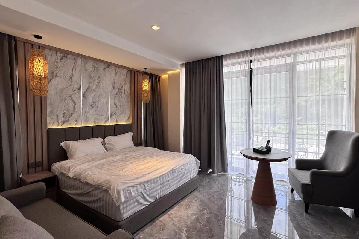 A modern hotel room with a large bed, a seating area with a table, and a TV.