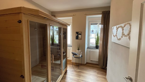 Ein geräumiger Flur mit einem Holzschrank, einem Heizkörper und einem Fenster mit Vorhängen.