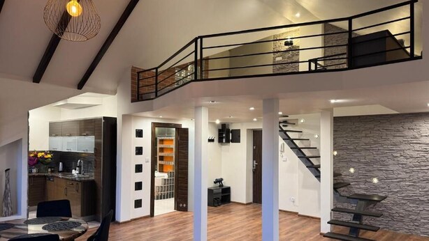 A spacious living area with a dining table, a staircase, and a kitchen in the background. - Carpatia Loft (Unknown)