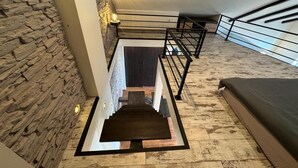 A modern staircase with a stone wall on one side and a view of the sky on the other. - Carpatia Loft (Unknown)