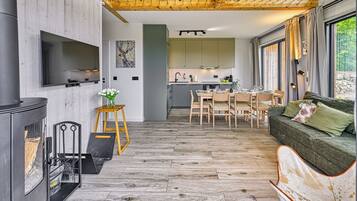 A modern interior with a wooden floor, a dining area, a sofa, and a kitchen.