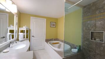 A bathroom with two sinks, a bathtub, and a shower area.