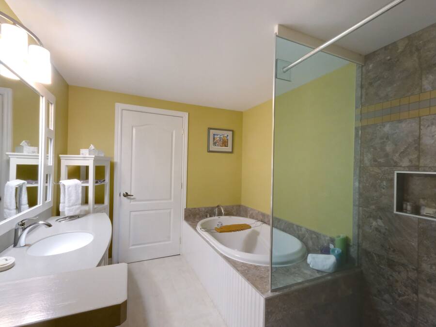 A bathroom with two sinks, a bathtub, and a shower area.