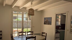 A dining area with a round table, chairs, and a hanging light fixture. - Typical Landes villa Seignosse le Penon (Seignosse)