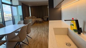 Une chambre d’hôtel moderne comprenant un coin repas, un canapé et un comptoir de cuisine avec une bouteille de liquide vaisselle.